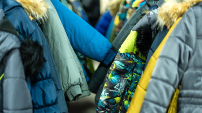 An image of racks of children's winter coats, a free clothing item distributed by Community Threads.